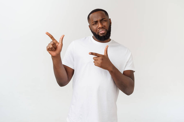 Young amazed African American pointing his finger at white background with copy space for your advertisement - Foto, imagen