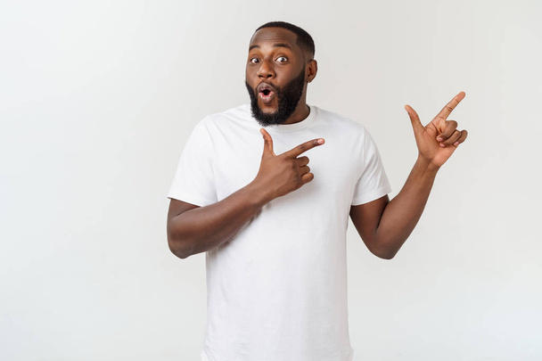 Jonge verbaasd Afro-Amerikaanse wijzend zijn vinger op witte achtergrond met kopieerruimte voor uw advertentie - Foto, afbeelding