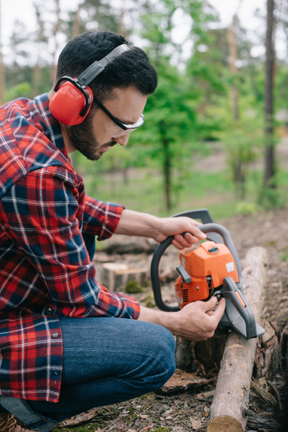森林のチェーンソーを固定するノイズキャンセリングヘッドフォンの木材マン - 写真・画像