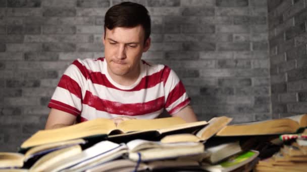 Man student boring reading book at library with a lot of books in university. Student disheartened reading book for examination. - Video