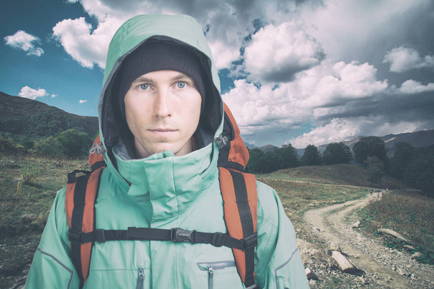 Young male hiker on cloudy landscape background looking at camera. Front view. Active lifestyle and tourism. - Fotó, kép