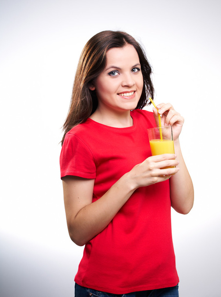Attractive young woman in a red shirt. Holding a glass of juice. - Φωτογραφία, εικόνα