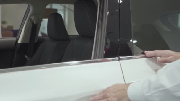 Portrait attractive confident bearded businessman sits in the vehicle and inspects newly purchased auto from the car dealership. Car showroom. Advertising concept. - Materiaali, video