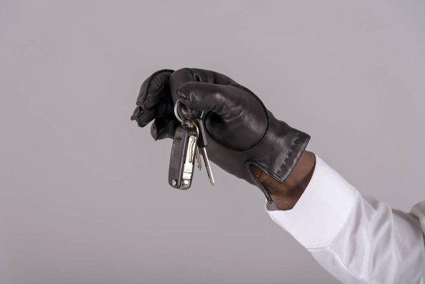England, Großbritannien. Mai 2019. männliche Hand trägt einen schwarzen Lederhandschuh mit Zündschlüssel, - Foto, Bild