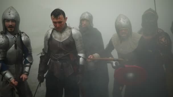 Ομάδα μάχης των μεσαιωνικών ιπποτών των σταυροφόρων στέκονται σε βραχίονες και κράνη με τα σπαθιά και τις ασπίδες τους να ετοιμάζονται να επιτεθούν ενάντια στο φόντο του καπνού στο δάσος. - Πλάνα, βίντεο
