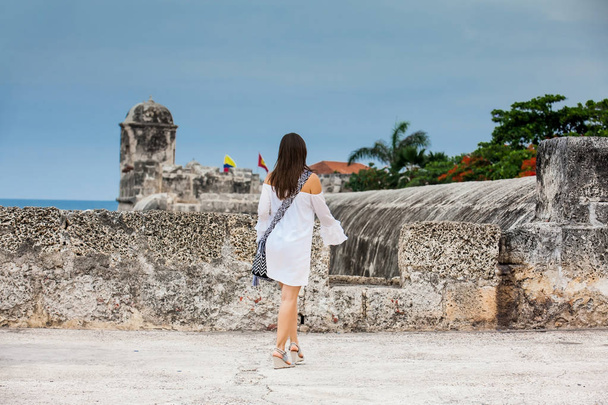 Belle femme en robe blanche assise seule aux murs entourant la ville coloniale de Cartagena de Indias
 - Photo, image