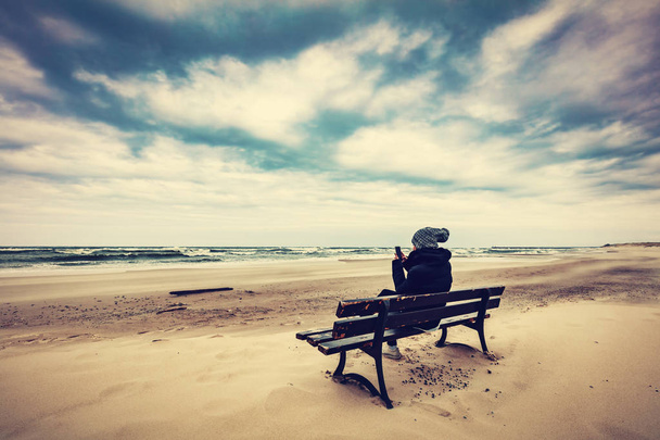 Mulher sentada no banco na praia de areia
 - Foto, Imagem
