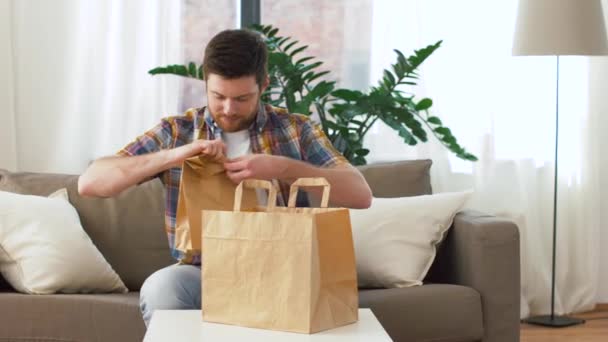 smiling man unpacking takeaway food at home - 映像、動画