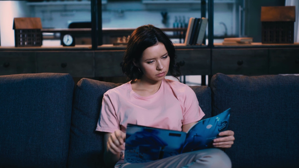 внимательная молодая женщина читает дневник, сидя дома на диване
 - Кадры, видео