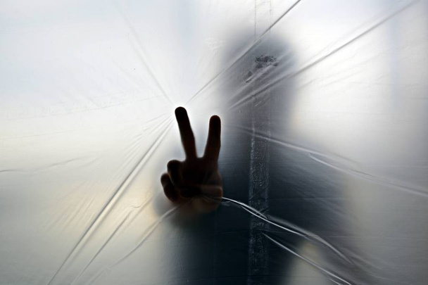 Silhouette d'une main fantôme derrière du plastique transparent
  - Photo, image