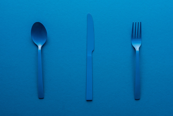 colher de plástico azul, faca e garfo no fundo azul
 - Foto, Imagem