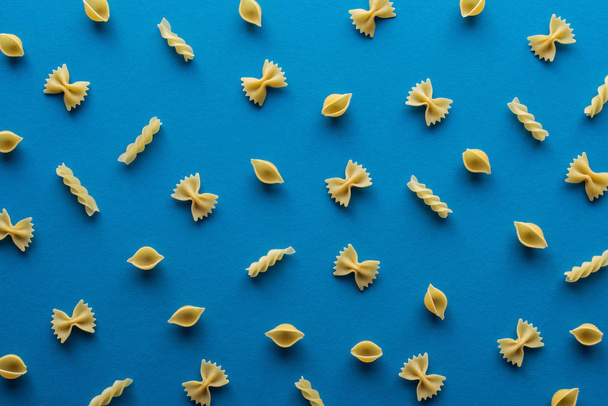 top view of different uncooked pasta on blue background - Fotó, kép