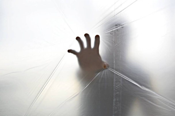 Σιλουέτα ενός χεριού φάντασμα πίσω από διαφανές πλαστικό  - Φωτογραφία, εικόνα