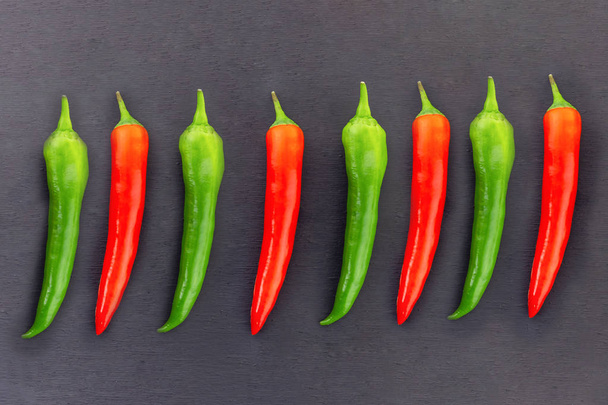 paralelní zelená červená chilli papriček, postupné opakované kontrastující zeleninové pozadí - Fotografie, Obrázek