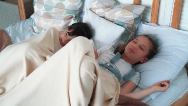 Two little cute girls lies in bed, smile and laugh, slow motion - Footage, Video