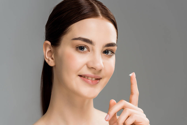 cheerful naked woman with cosmetic cream in finger isolated on grey  - Photo, image