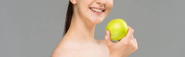 panoramic shot of happy woman smiling while holding green apple isolated on grey  - Foto, Imagem