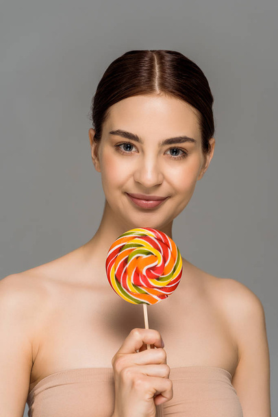 happy young woman holding colorful lollipop isolated on grey  - Фото, зображення