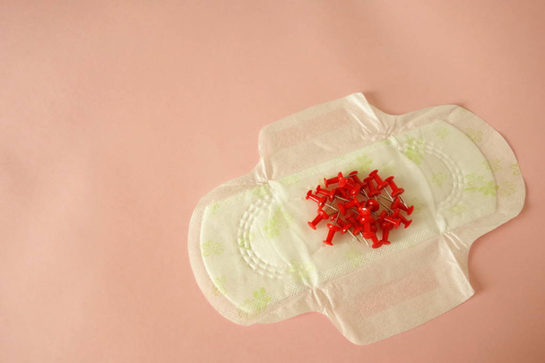Menstruele pad met rode pinnen op roze achtergrond, kopieerruimte voor uw ontwerp - Foto, afbeelding