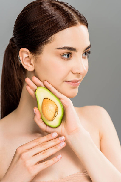 beautiful young woman holding avocado half isolated on grey  - Foto, imagen