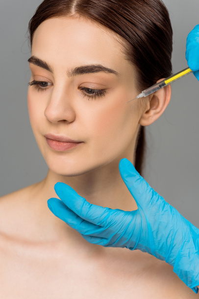 cropped view of plastic surgeon making beauty injection to attractive woman isolated on grey  - Фото, изображение