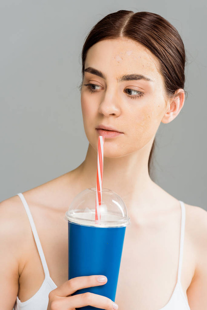 fiatal nő a problémás bőr gazdaság műanyag pohár izolált szürke  - Fotó, kép