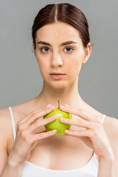 brunette young woman with face scrub on skin holding apple isolated on grey  - Foto, Imagen