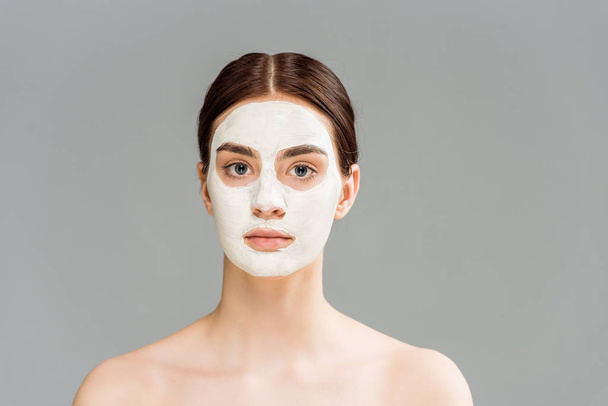 nahá mladá žena s hliněnou maskou na obličeji izolovaná na šedé  - Fotografie, Obrázek