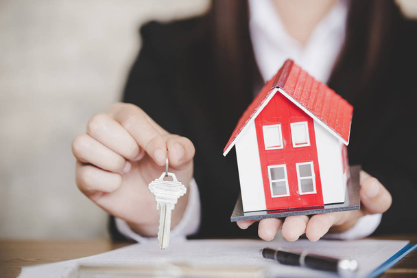 Агент по недвижимости с моделью дома и ключами
  - Фото, изображение