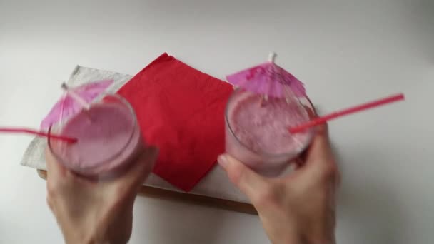zwei Gläser rosa Frucht-Smoothies Milchshake oder Smoothie oder Cocktail, die auf einen Tisch auf weißem Hintergrund gelegt werden. gesunde saftige Vitamin-Drink-Diät oder veganes Rohkost-Konzept - Filmmaterial, Video