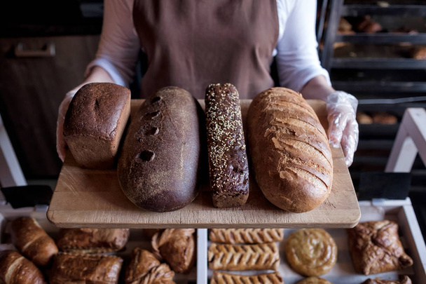 Seller holding a tray with fresh loaf of different bread - Foto, Imagem