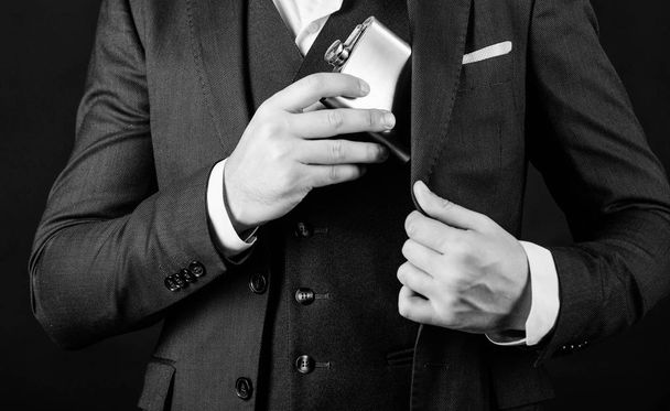 male with beard put whiskey flask in pocket. man has bad addiction. businessman in suit. bachelor and single. man drink alcohol. drinking whiskey from bottle. whiskey on business meeting - Foto, afbeelding