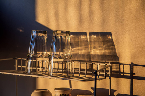 посуда и стаканы на сушилке на кухне при закате
 - Фото, изображение