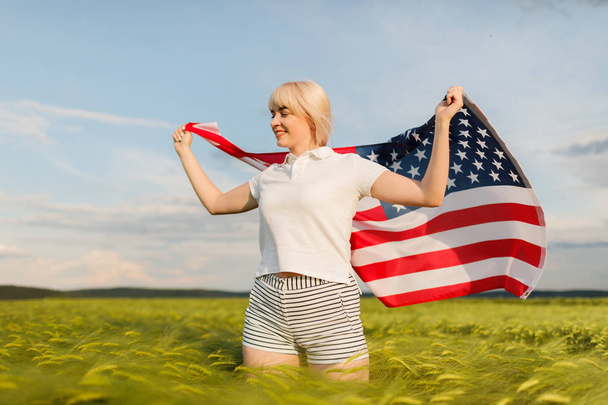 Woman holding American flag in wheat field. Patriots of America. Girl celebrating 4th of july. - Φωτογραφία, εικόνα