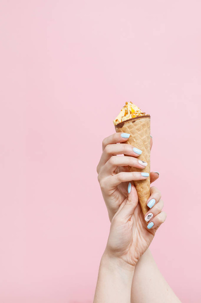 Mujer sosteniendo helado en un cono de gofres sobre fondo de color
. - Foto, Imagen