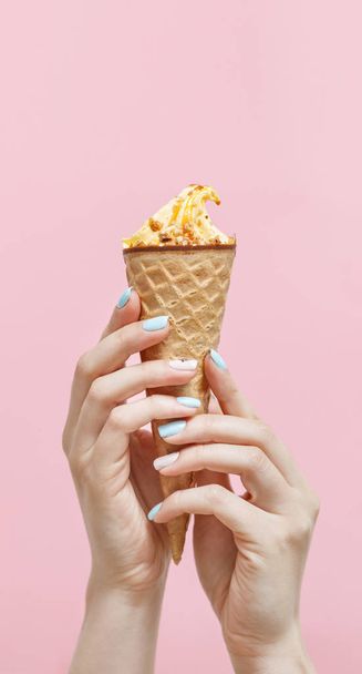 Woman holding Ice Cream in a waffles cone on color background. - Zdjęcie, obraz