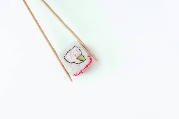Roll with crab meat, cucumber and flying fish roe on wooden sticks. White background. - Foto, afbeelding