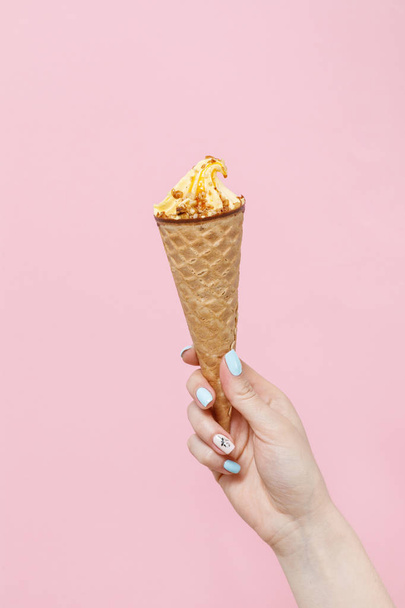Woman holding Ice Cream in a waffle cone on color background. - Foto, afbeelding