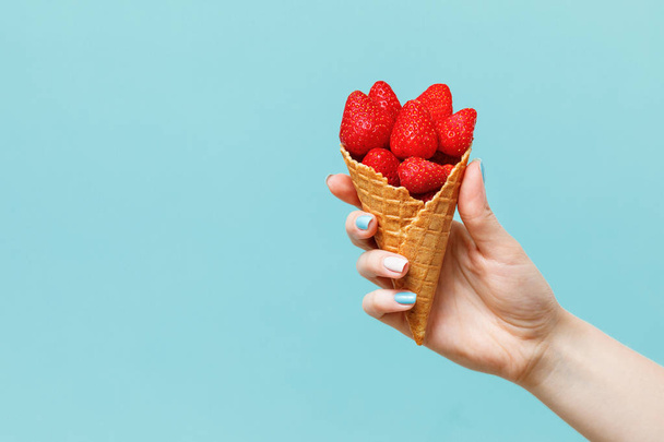 Waffle cone with strawberries  in female hand. Fresh summer fruits. - Photo, Image