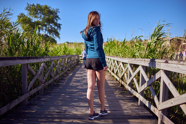 junge Frau läuft an einem Holzsteg vorbei - Foto, Bild