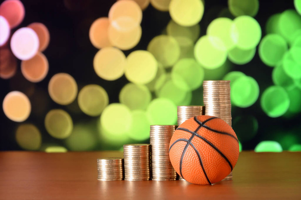 Koszykówka i stosy złotych monet w wykres wzrostu na tle niewyraźne bokeh - Zdjęcie, obraz