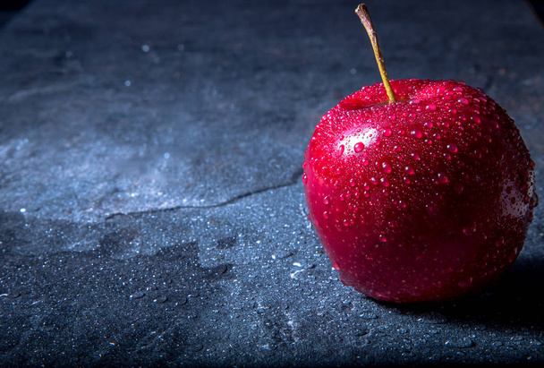 a wet, red juicy apple lies on a marble bar counter. dark background - Foto, imagen