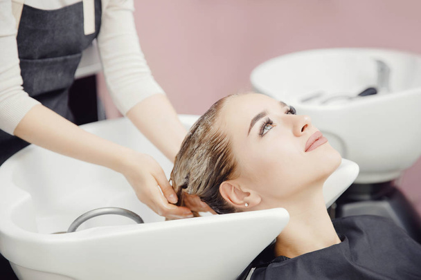 Beautiful blond woman getting hair wash in beauty salon - Photo, Image