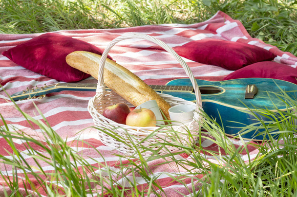 summer picnic basket with apples and guitar lie on a plaid with pillows heat - Φωτογραφία, εικόνα
