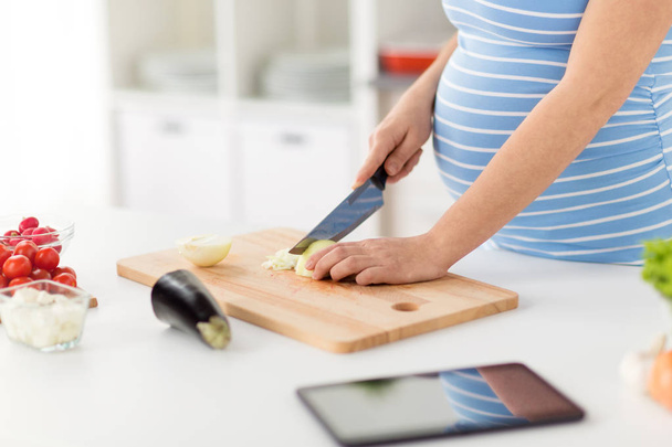 close up of pregnant woman cooking food at home - Foto, imagen