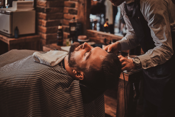 Thendy hairdresser at modern barbershop is working on clients haircut. - Foto, Imagem