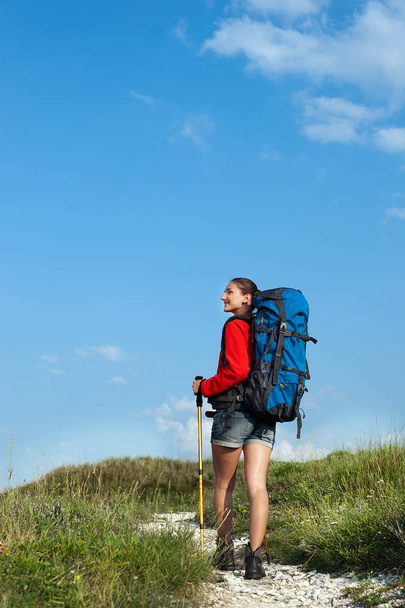 Mosolygó fiatal nő túrázás, a hegyi ösvényen  - Fotó, kép