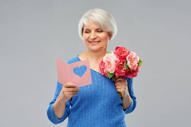 happy senior woman with flowers and greeting card - Zdjęcie, obraz