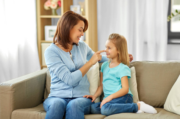 mother and daughter sitting on sofa at home - Foto, imagen