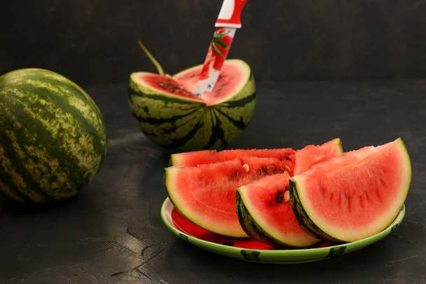 Stücke von saftigen Wassermelonen liegen auf einem Teller vor dunklem Hintergrund - Foto, Bild